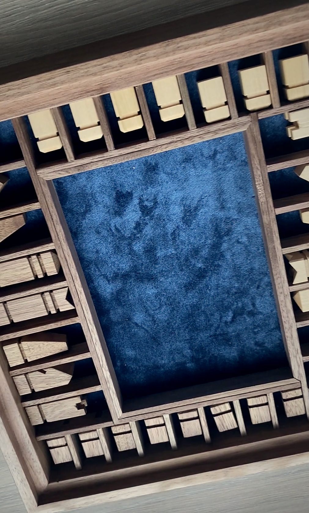 Blue-lined storage compartments for the chess pieces beneath the board
